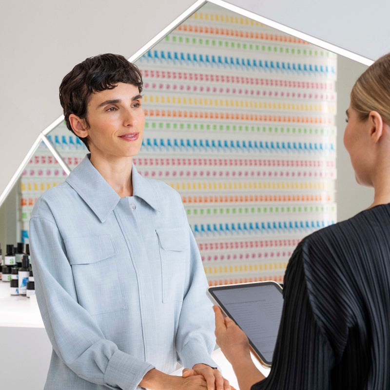 Two women in a professional setting with a colorful abstract pattern in the background