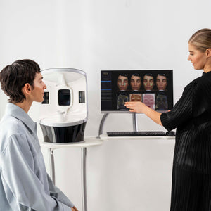 Two people interacting with a computer screen displaying facial recognition software.