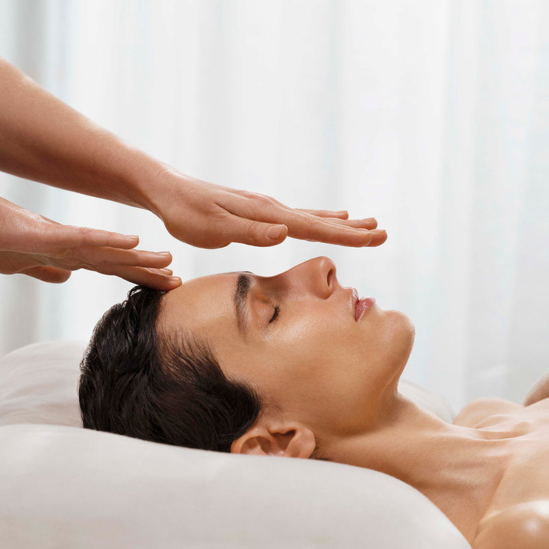 Person receiving a head massage with hands above their head on a white background