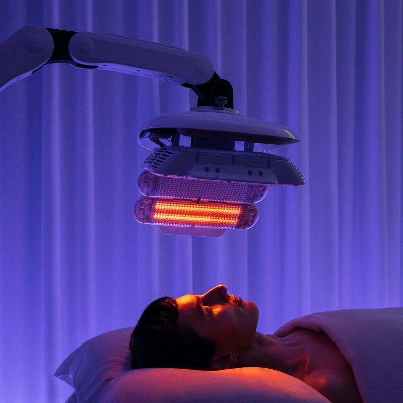Person receiving LED light therapy under a purple curtain
