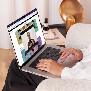 Person using a laptop with a video call on the screen in a cozy room.