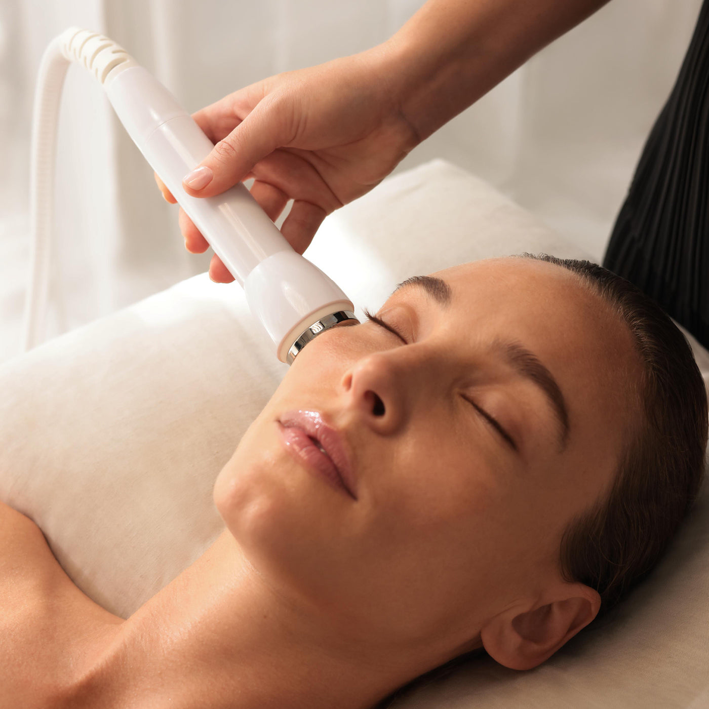 Person receiving a facial treatment with a handheld device on a white background